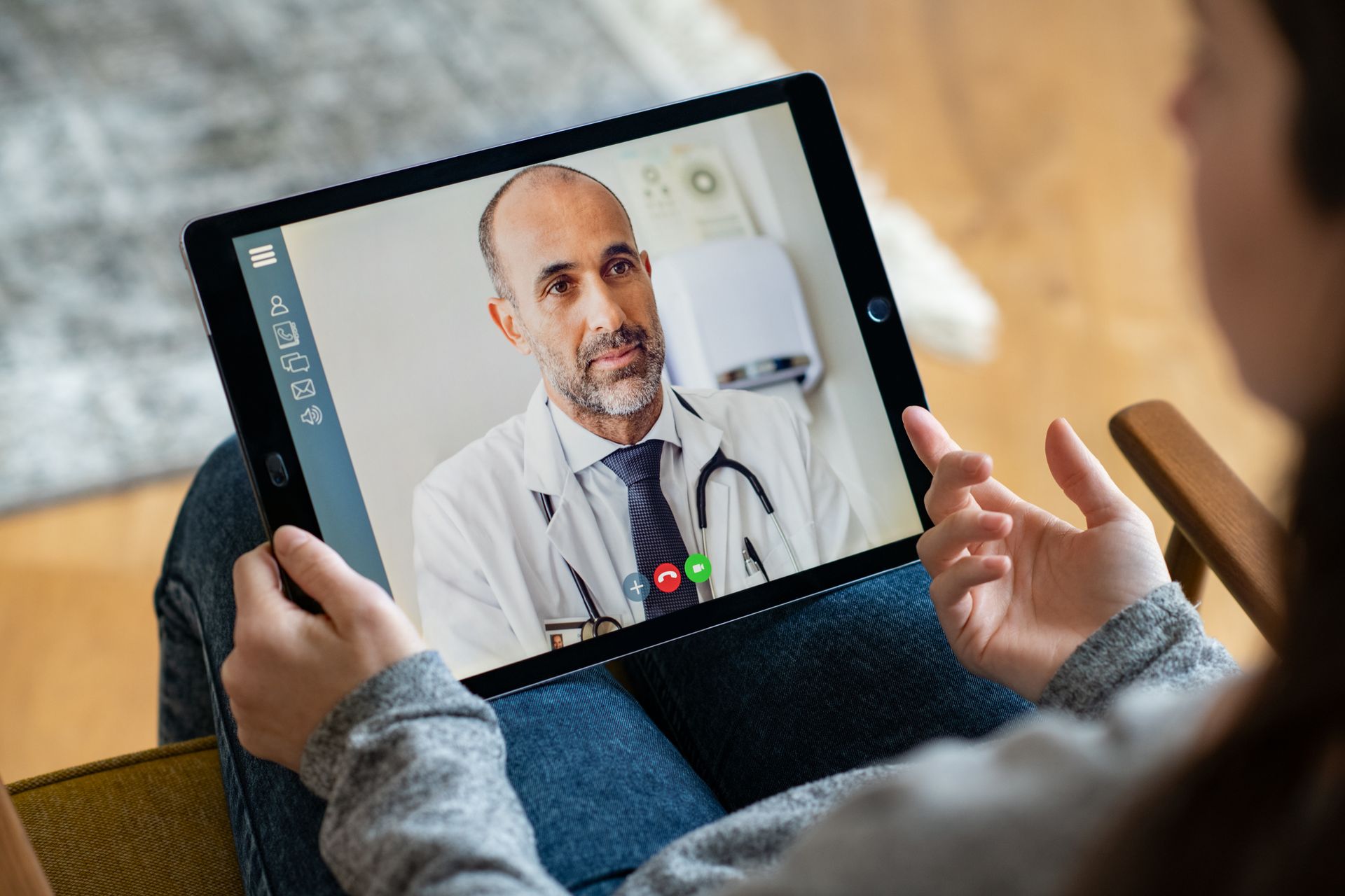 Chamada de vídeo com um médico em um tablet, mostrando um profissional de saúde de jaleco branco falando com o usuário.