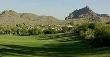 Green golf course with mountains in the background under a clear sky.