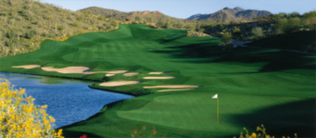 Golf course with green fairways, water, sand traps, and mountains in the background.