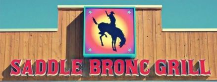 Saddle Bronc Grill sign featuring a cowboy on a bucking bronco in front of a blue sky.