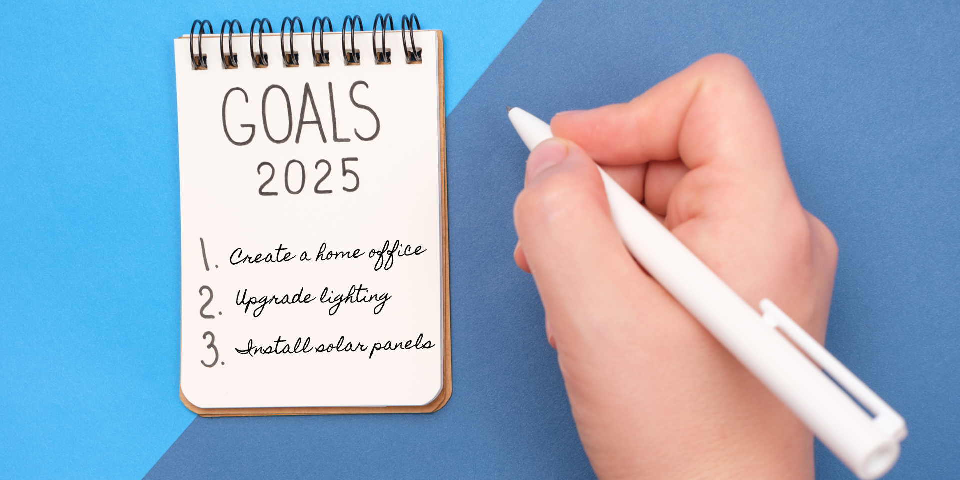 Notepad with list and hand with pen: Goals 2025, 1. Create a home office 2. Upgrade lighting 3. Install solar panels
