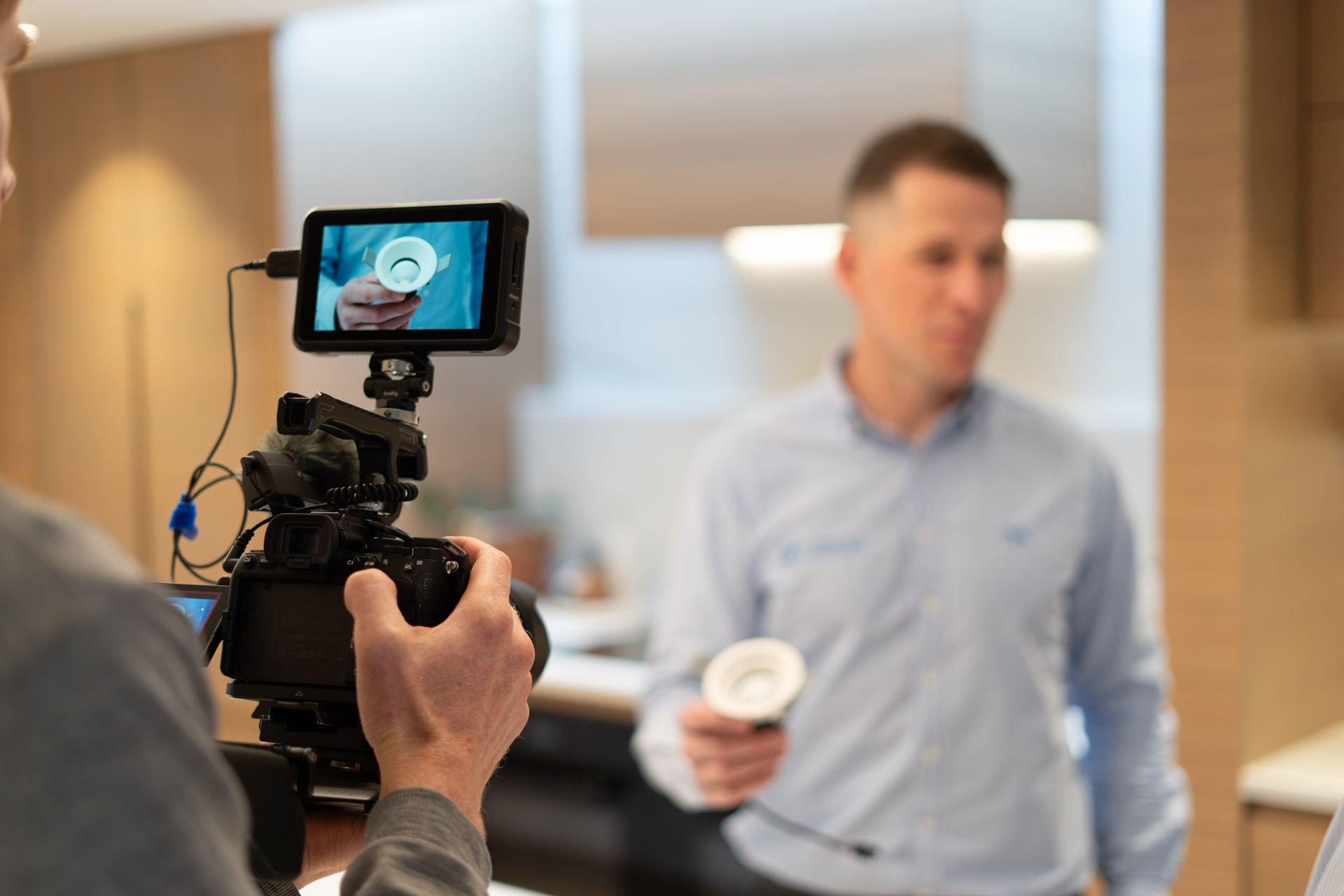 Jared Welsh of Christchurch Electrical holding a light fitting in a residential kitchen being filmed for brand video.