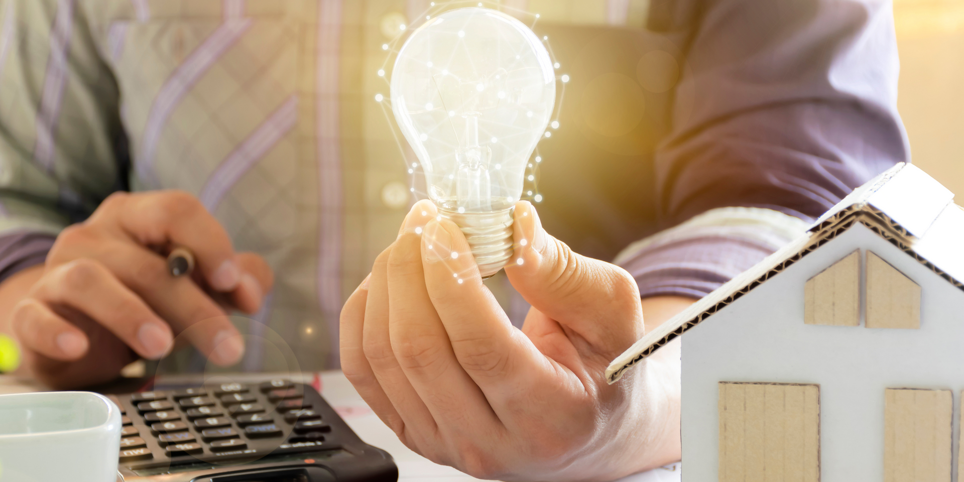 Man holding lightbulb with calculator and house
