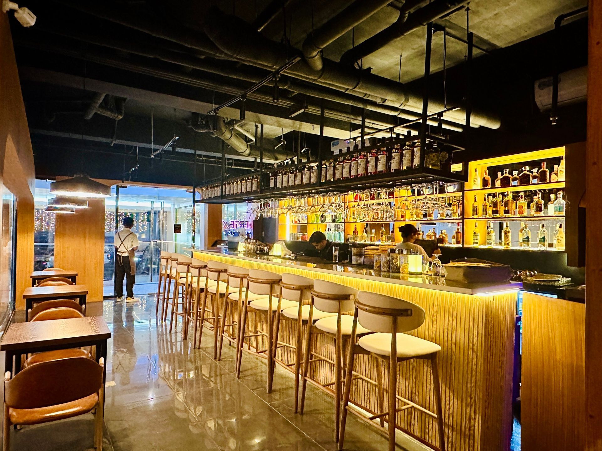 Stylish hotel bar with wood stools and backlit liquor shelves at The Belamy