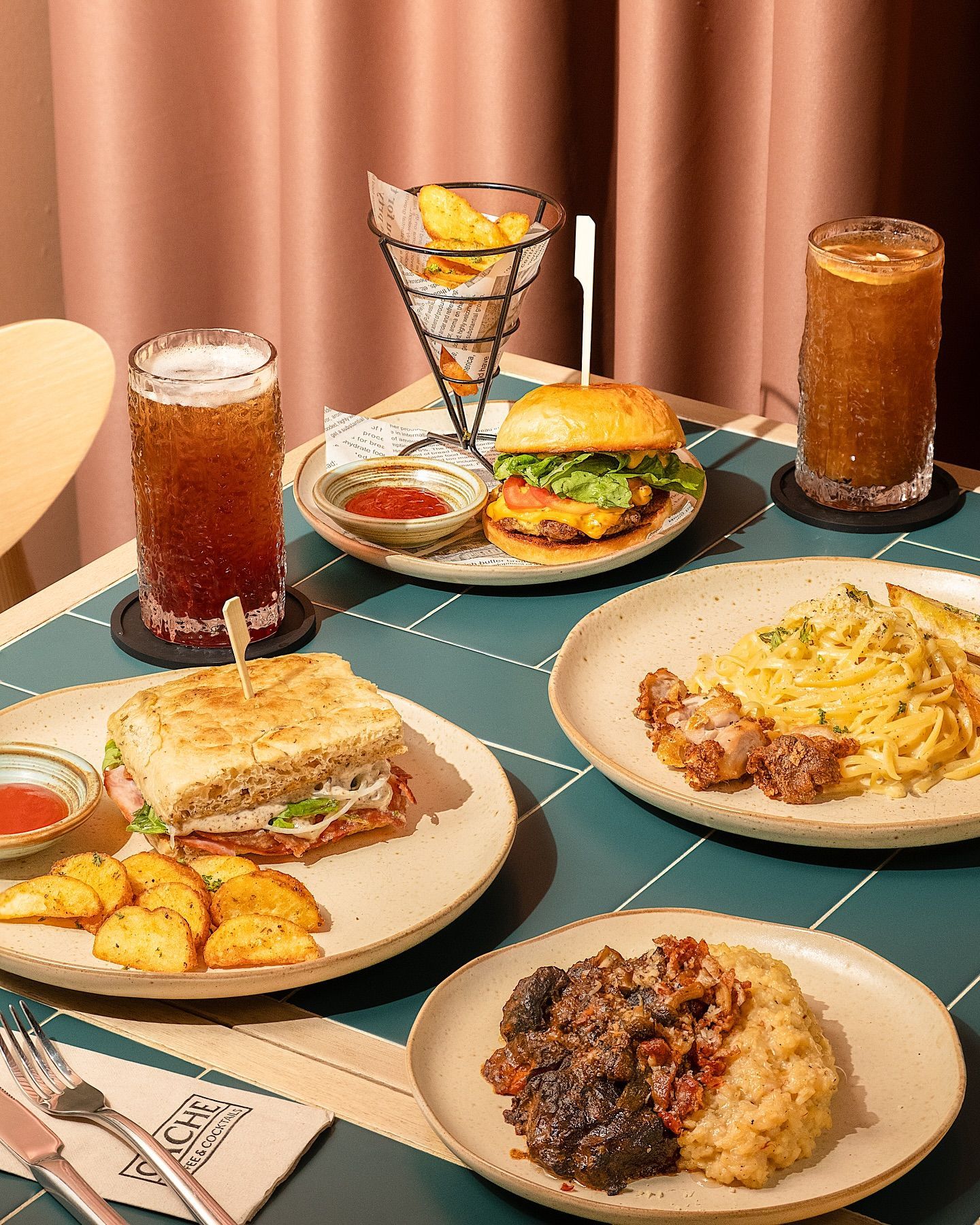 Café-style spread with burger, pasta, sandwich, risotto, and iced drinks