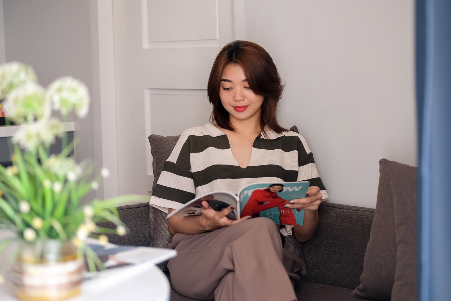 Woman relaxing on sofa reading fashion magazine at The Belamy House Makati