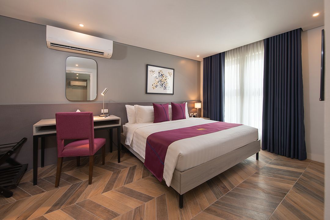 Belamy hotel room with a bed , desk , chair and mirror.