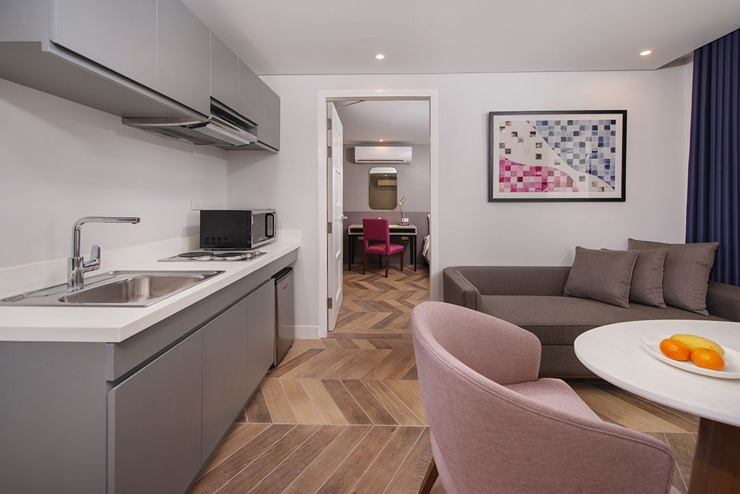 Modern apartment interior with a kitchen, living area, and dining room visible through an open doorway.