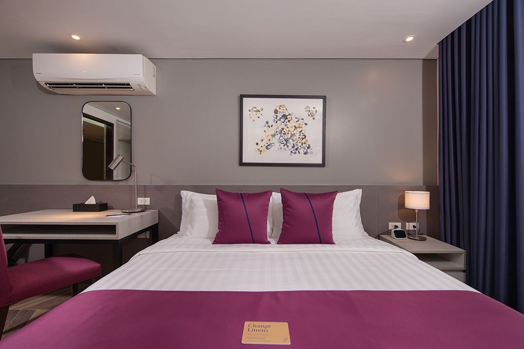 Elegant hotel room with magenta bedding at The Belamy House Makati