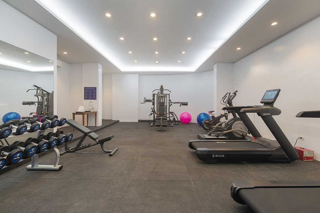 Modern hotel fitness center with treadmills and weights at The Belamy House