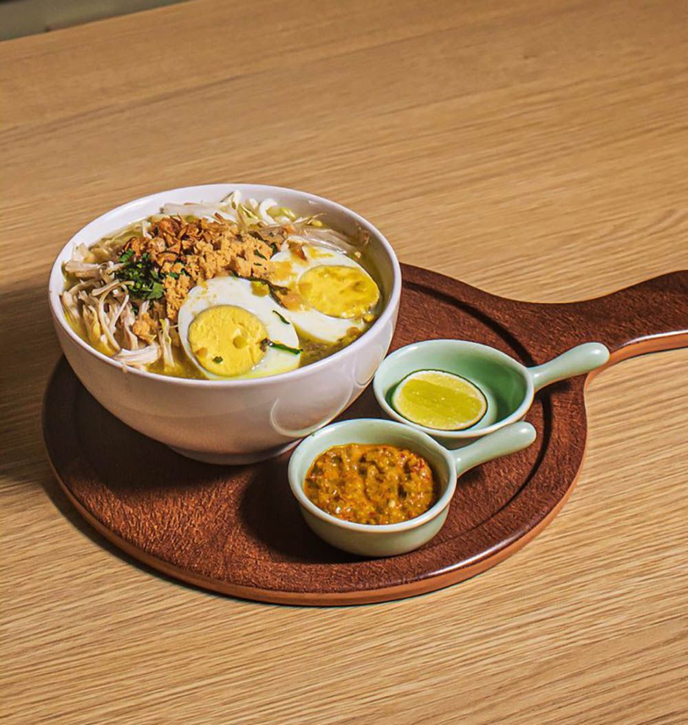 Three clay pot rice dishes with meat, vegetables, and chopsticks, on a table.