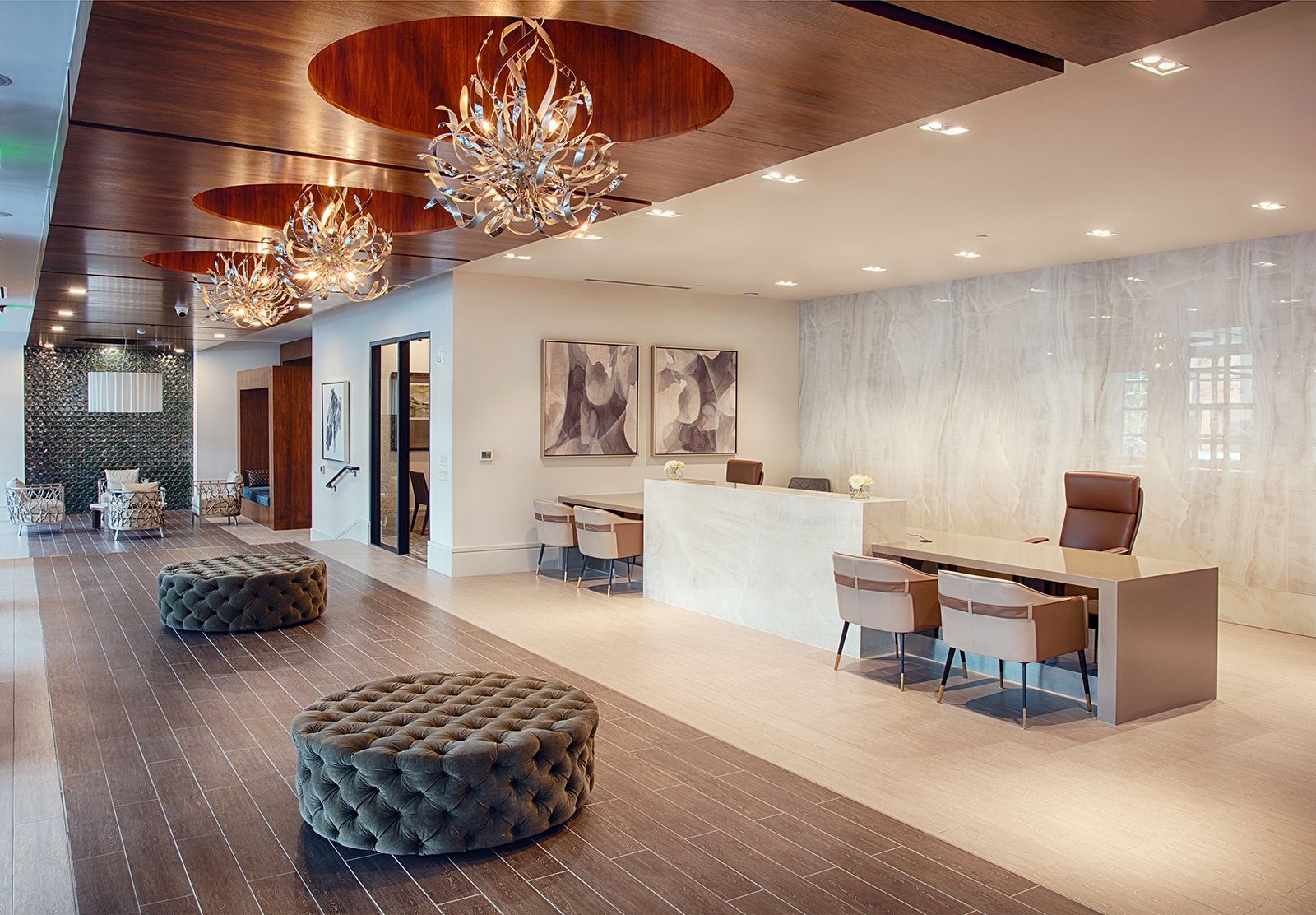 Luxurious lobby with crystal chandeliers, reception desk, tufted ottomans, and wood accents.