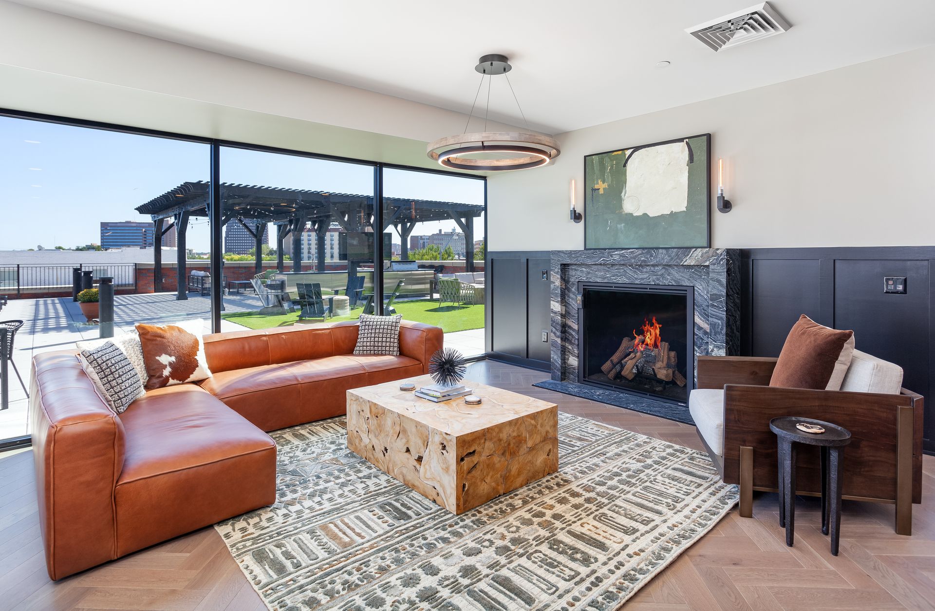 Upscale living room with large windows, leather sofa, fireplace, and outdoor view.