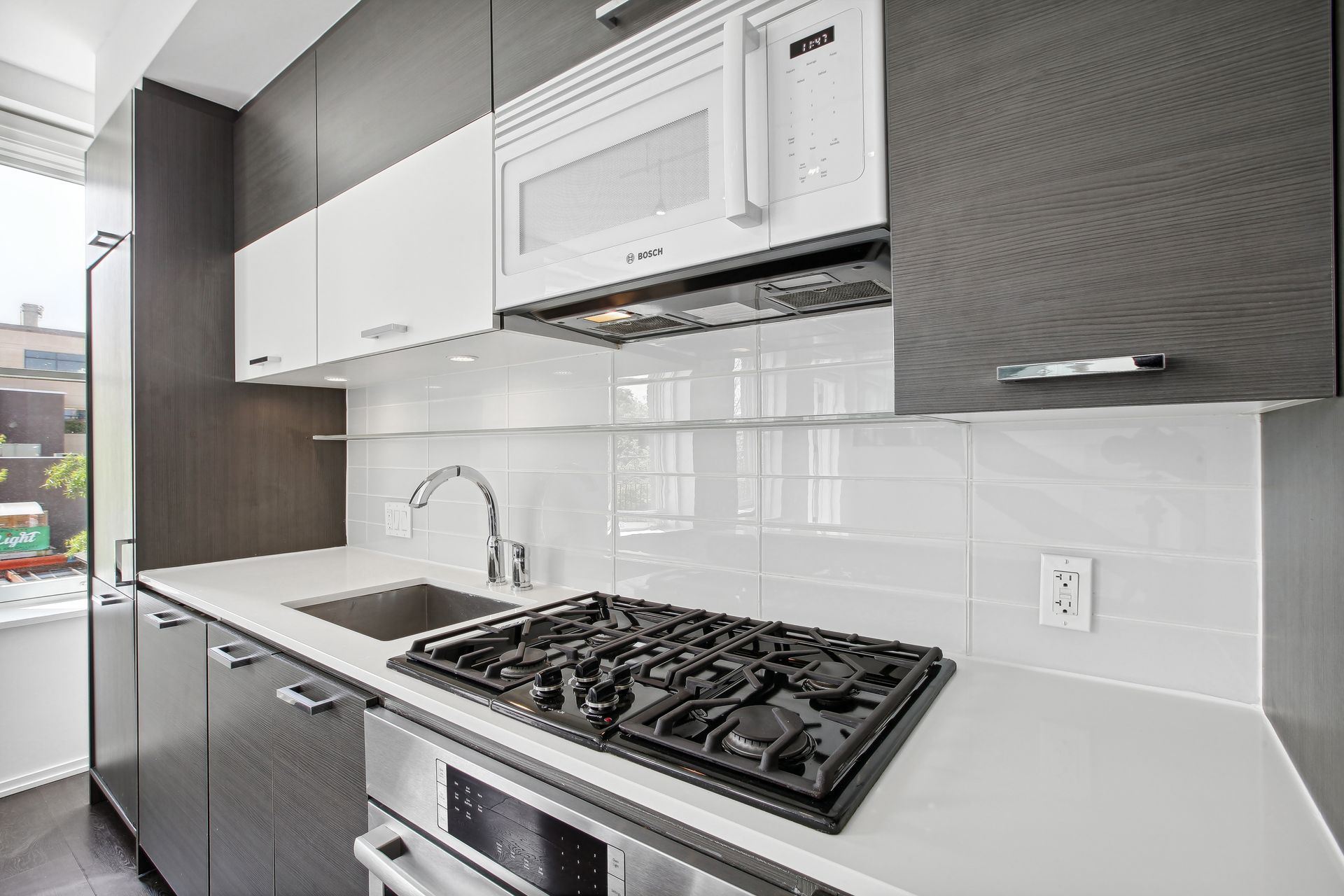 Modern kitchen with white countertops, gas stovetop, and stainless steel appliances.