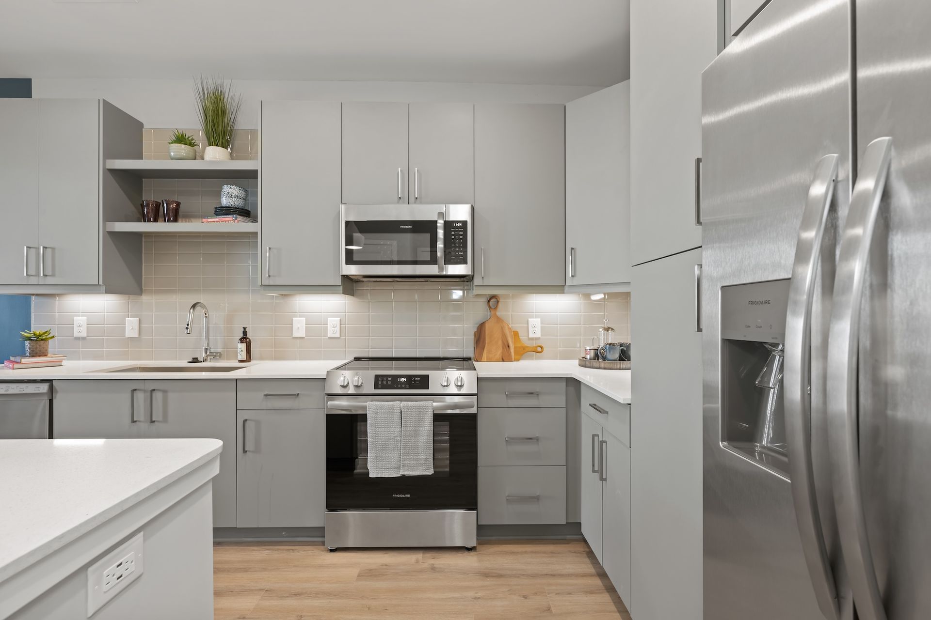 Modern kitchen with gray cabinets, stainless steel appliances, and light countertops.