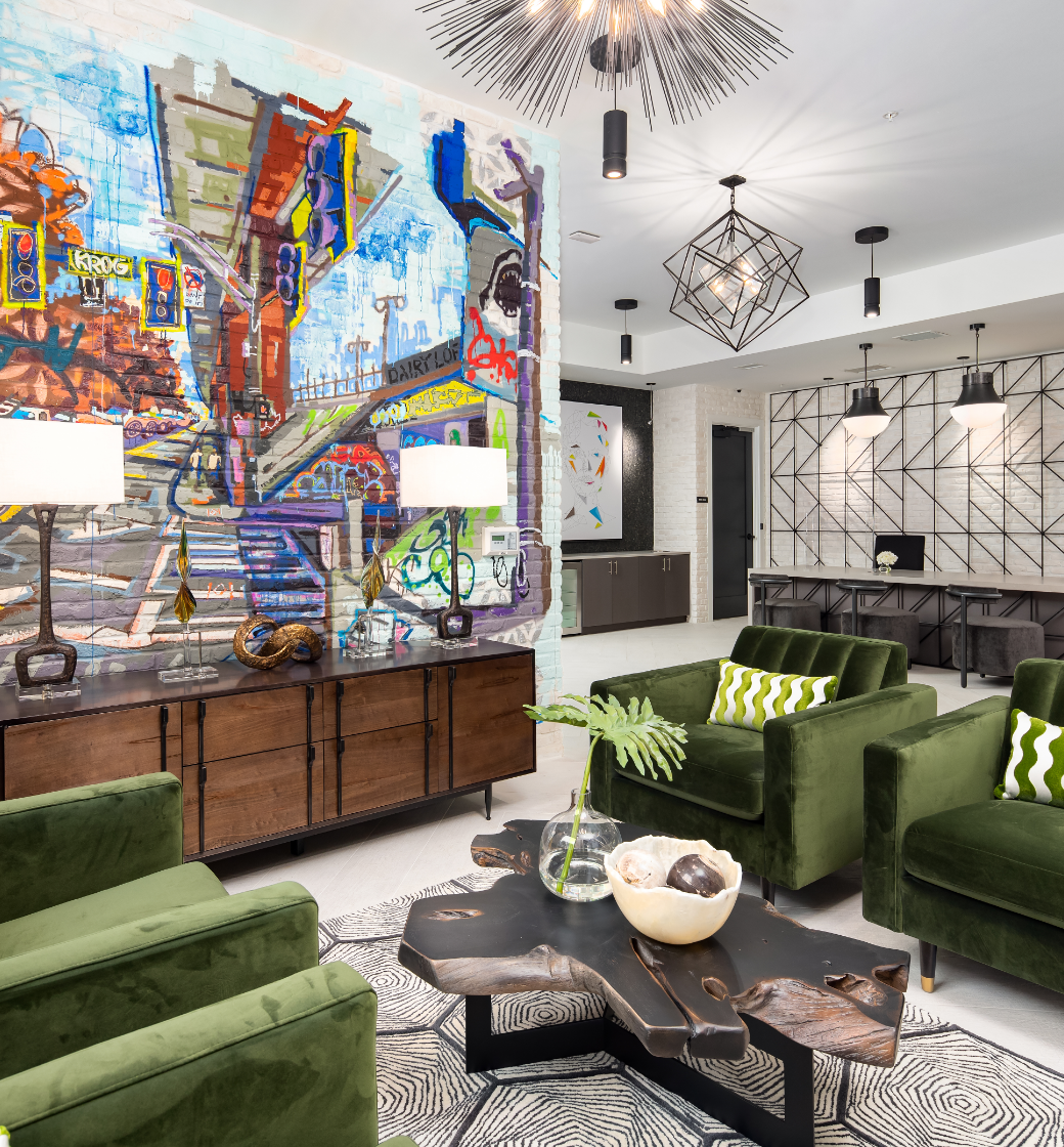 Modern living room with green chairs, colorful mural art, geometric lights, and a black coffee table