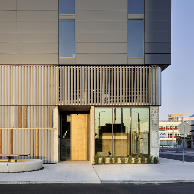 Modern building exterior with wooden door, concrete, and grey panels.
