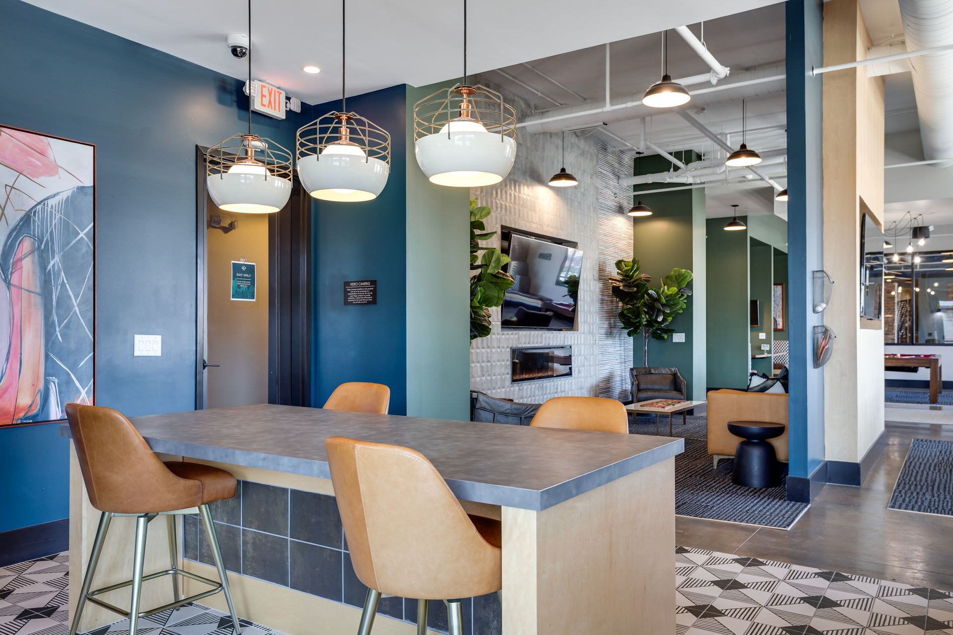 Modern lounge with bar seating, blue and green walls, and decorative pendant lights.