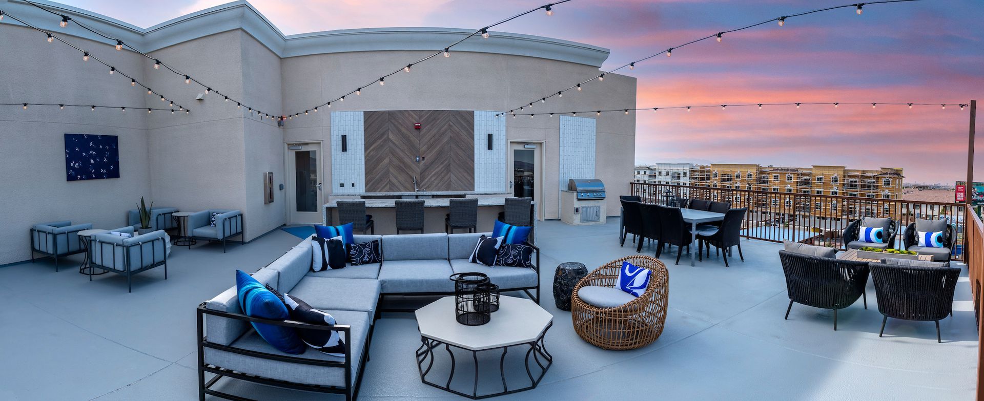 Rooftop patio with seating areas, string lights, and a sunset sky.
