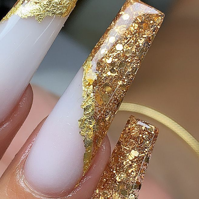 A close up of a person 's nails with gold glitter.