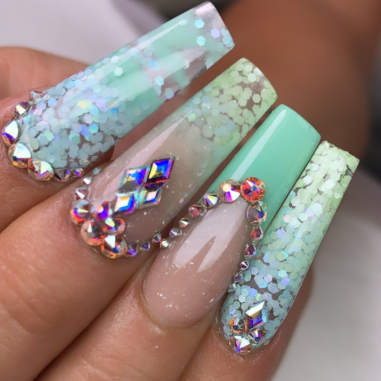 A close up of a person 's nails with rhinestones and glitter.