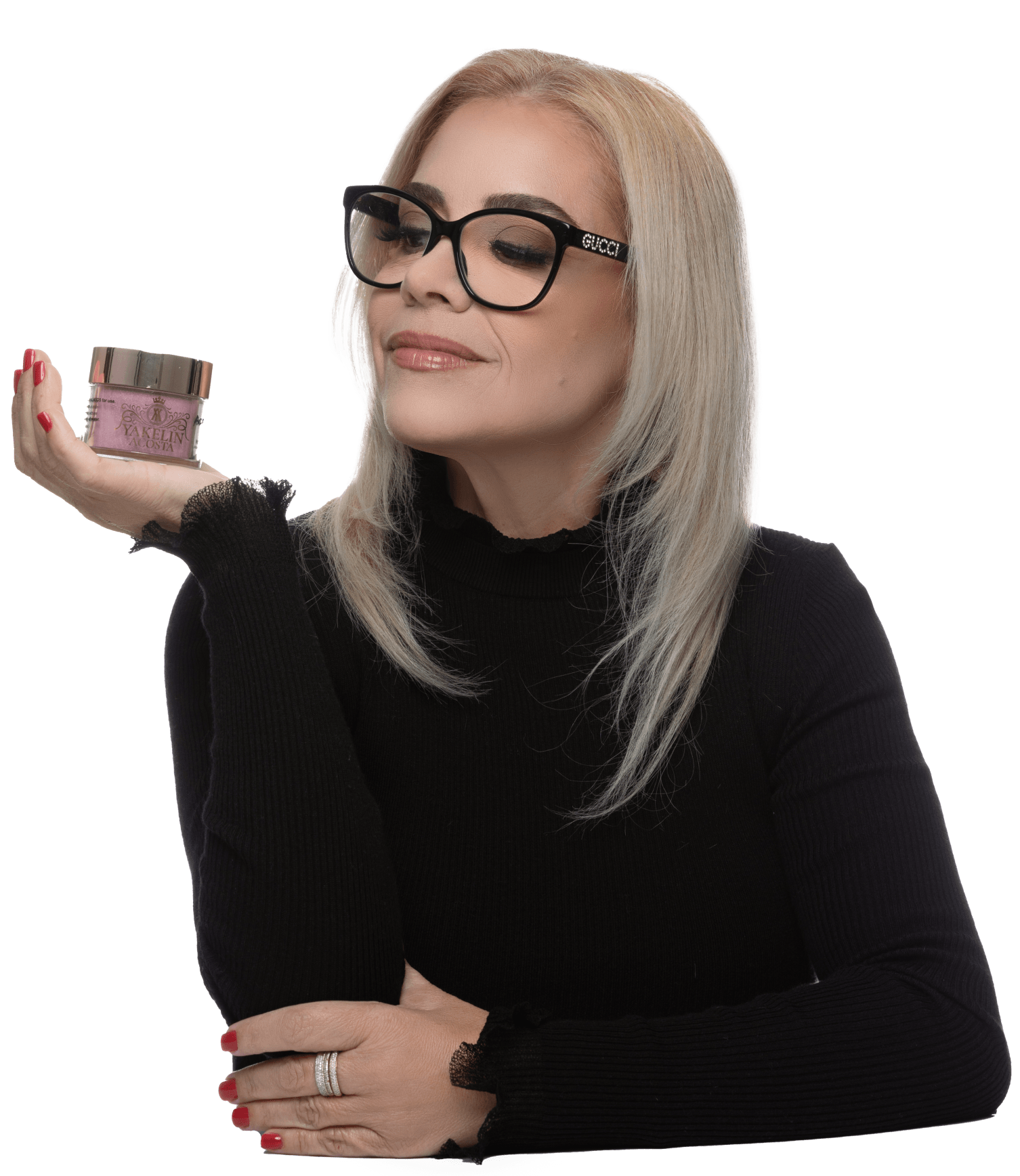 A woman wearing glasses is holding a jar of cream in her hand.