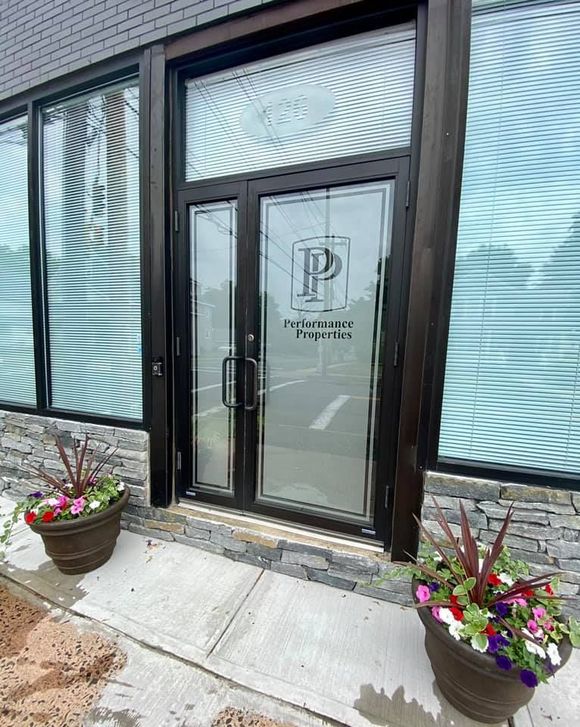 Glass office entrance with double doors, planter flowers, and frosted windows