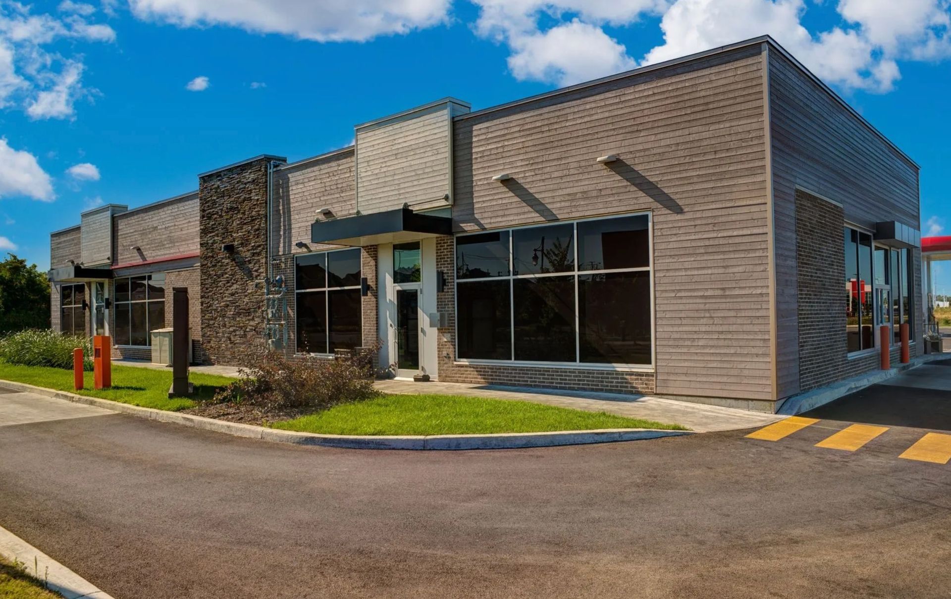Modern brick fast-food restaurant with drive-thru lanes under a blue sky