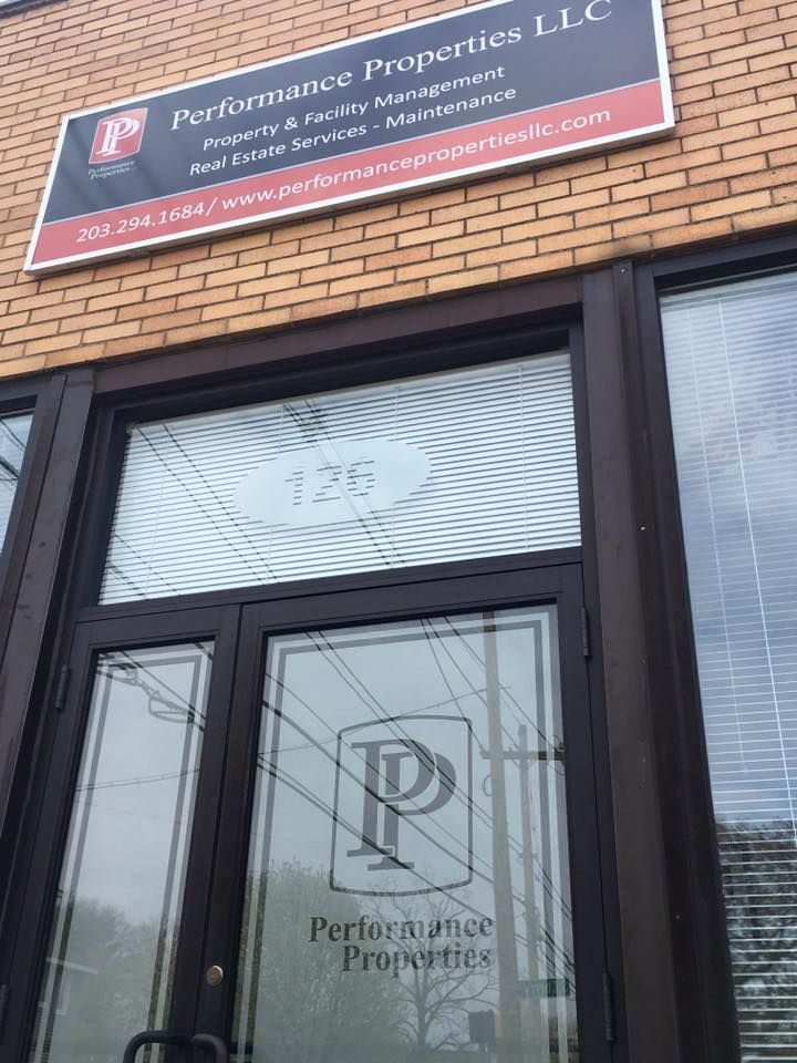 Brick storefront with a Performance Properties, LLC sign above a glass door and windows