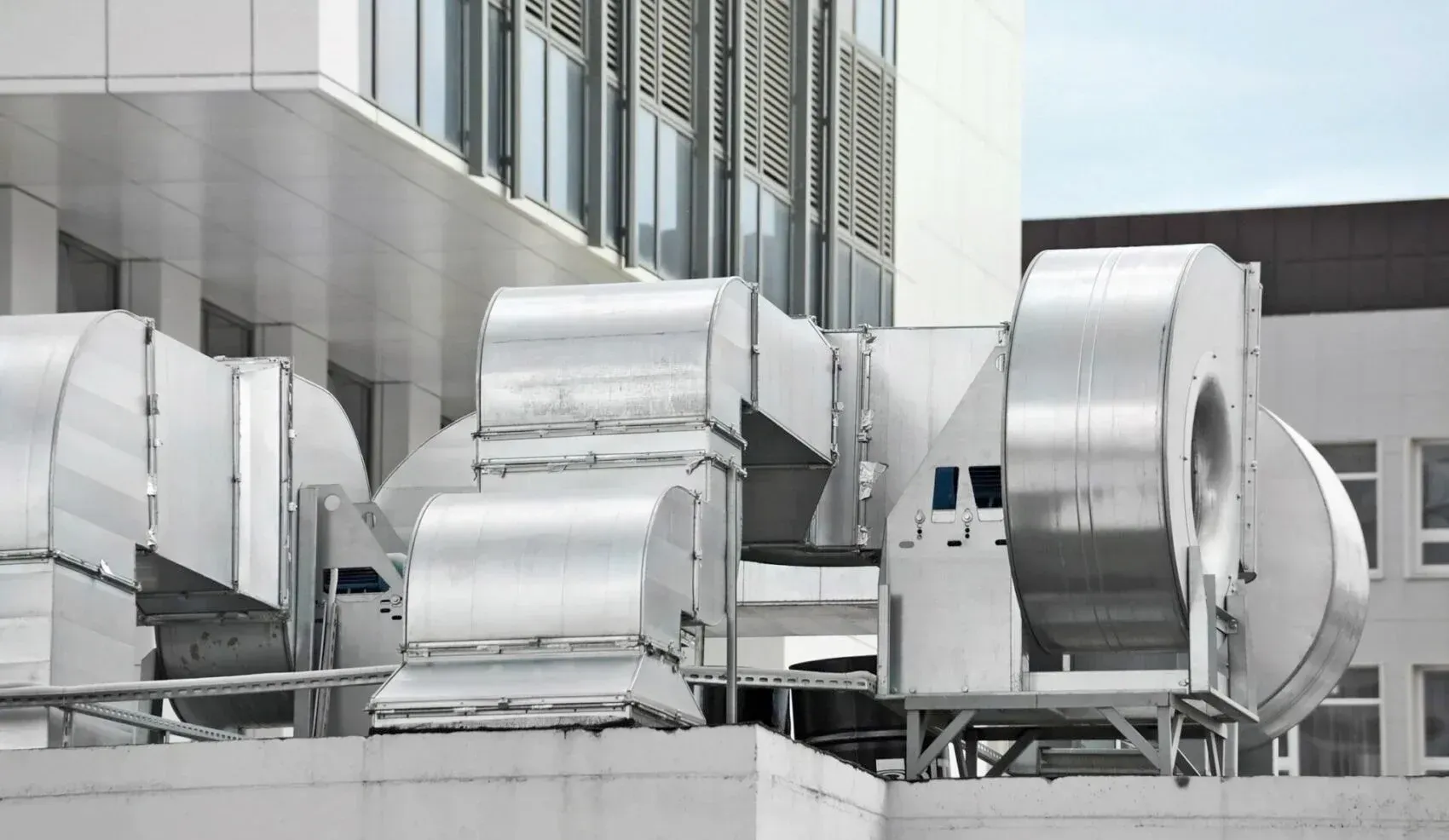 Rooftop HVAC vents and large silver industrial fans on a modern building
