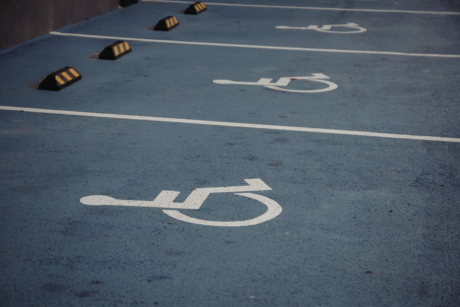Blue accessible parking spaces with white wheelchair symbols and wheel stops lined up in a lot