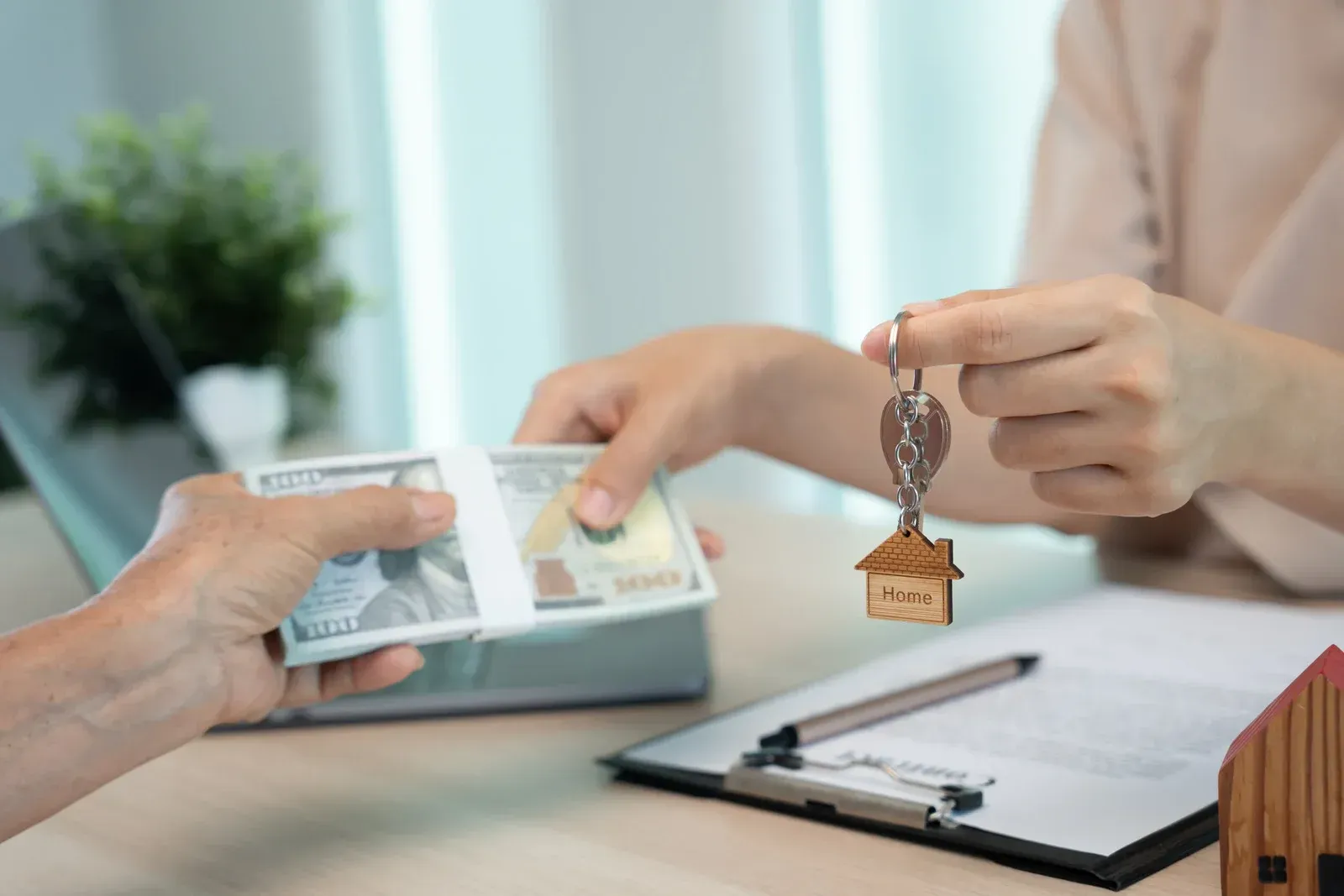 Handing over house keys during a real estate signing with documents and ID cards on the table