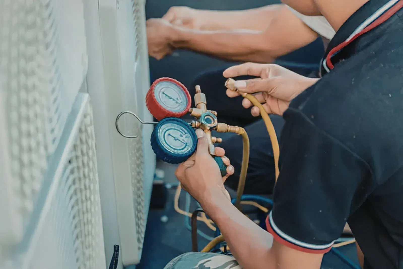 Technician checking gauges on industrial equipment with hoses attached