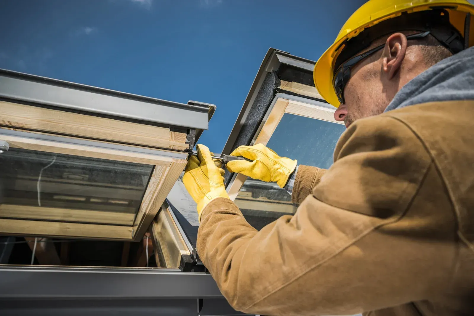Worker in hard hat installing a window frame on a house exterior