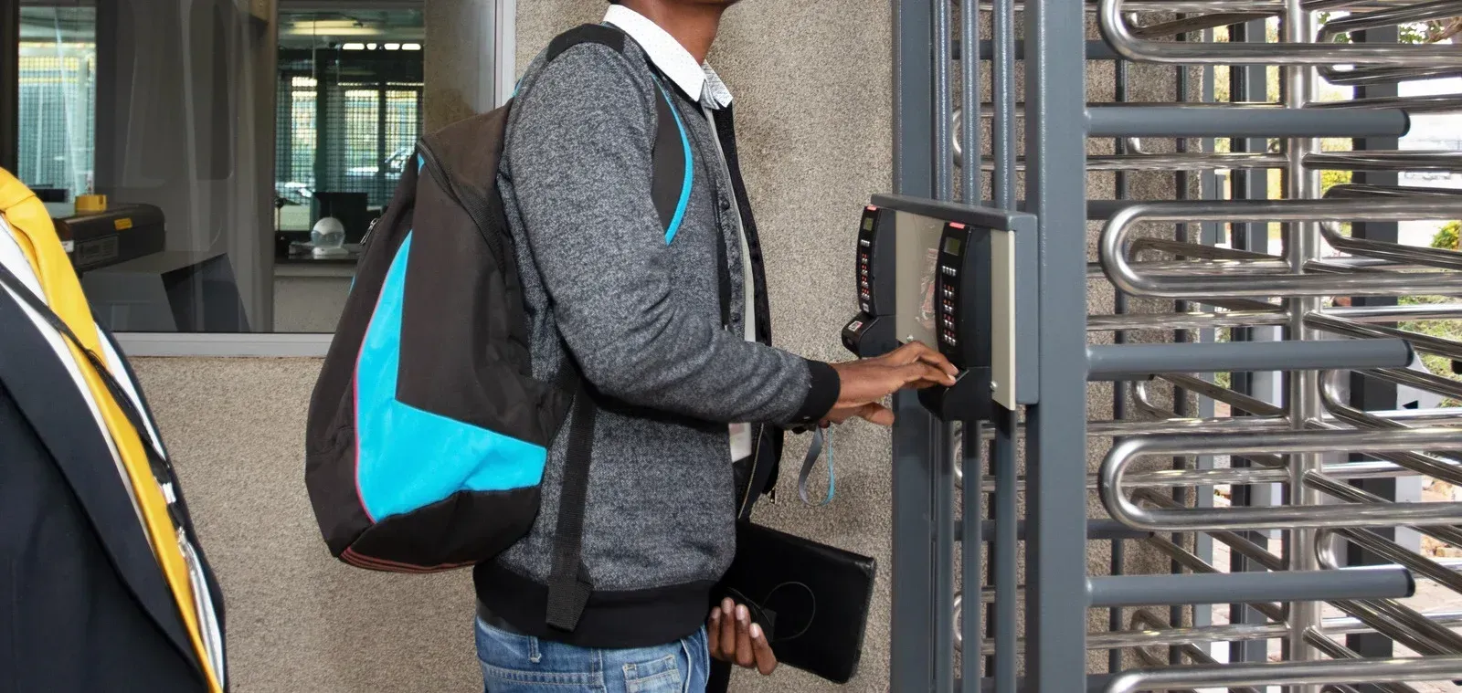 Person with backpack swipes a card at a turnstile entrance