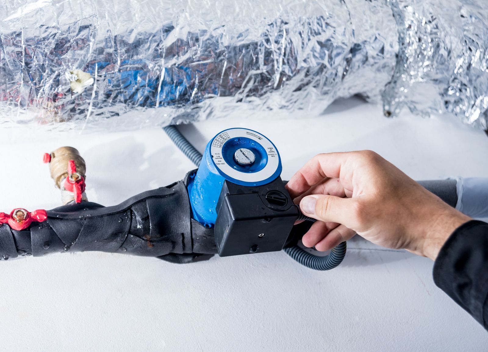 Hand holding a black-and-blue electric knife near wrapped meat on a counter