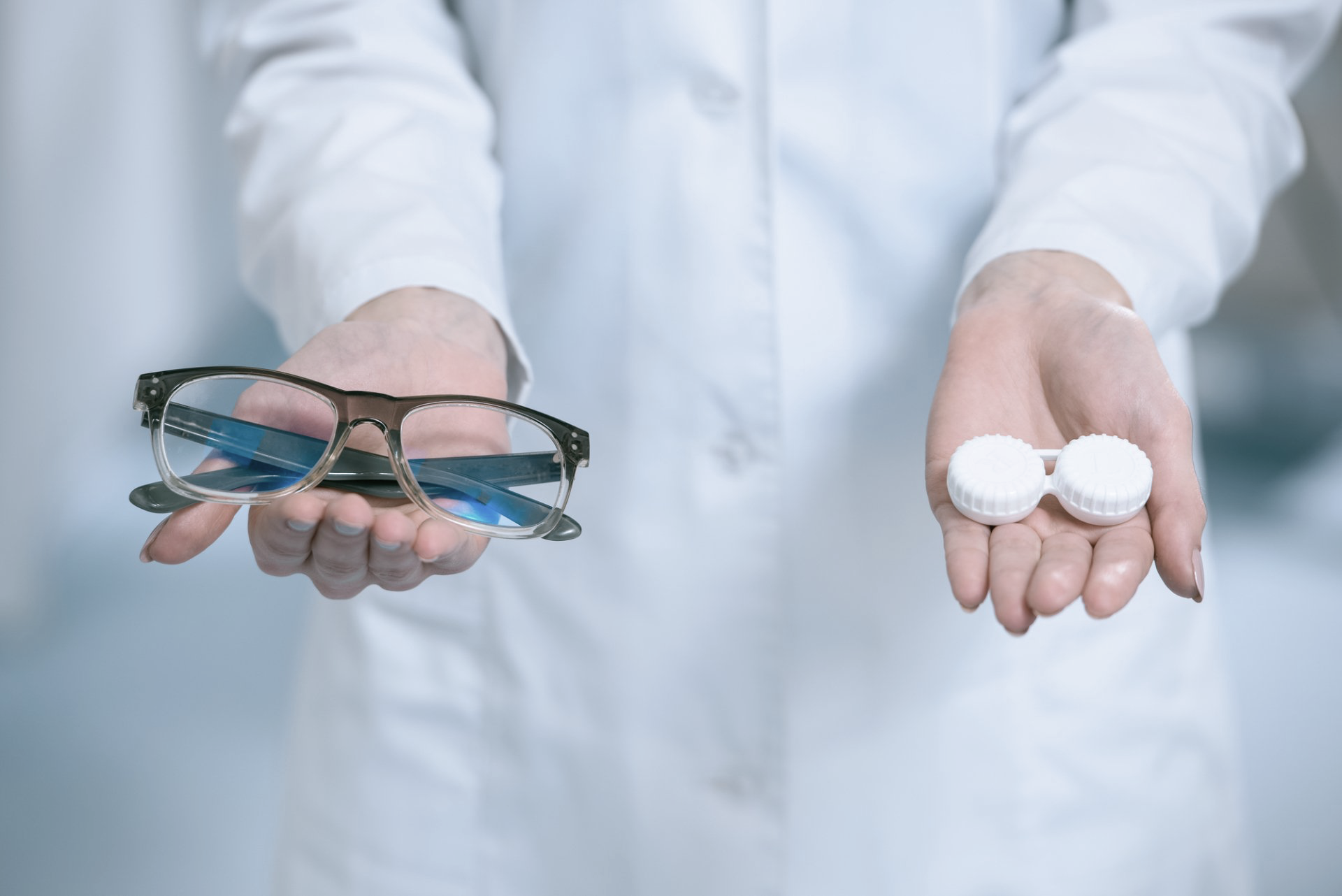 Optician-holding-a-pair-of-glasses-in one-hand-and-contact-lenses-in-the-other 