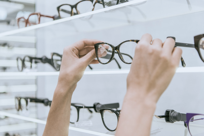 Optician-arranging-designer-spectacles-on-shelves.