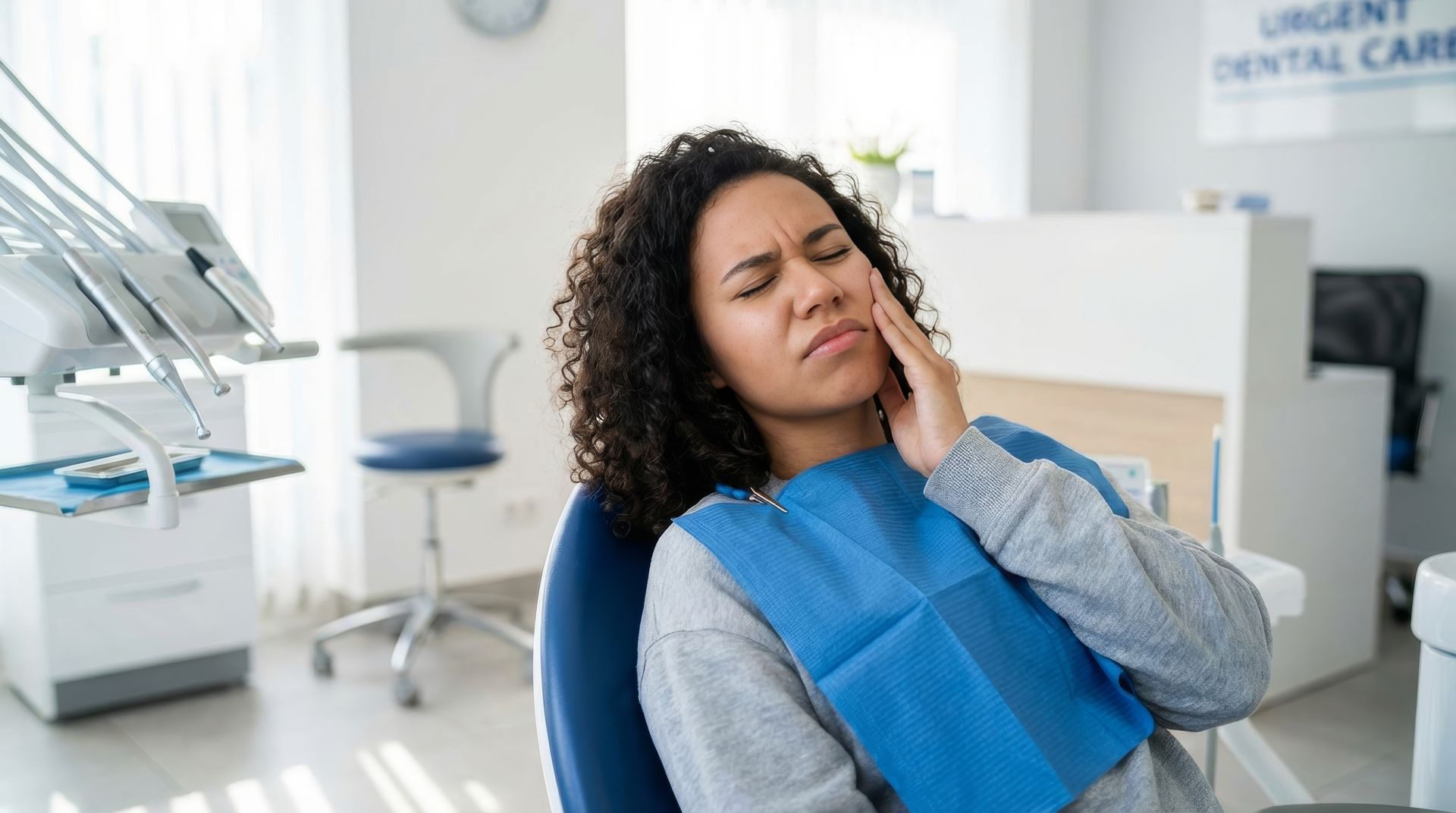 Woman holding her jaw in pain in a dental chair while waiting to be seen by the emergency dentist.