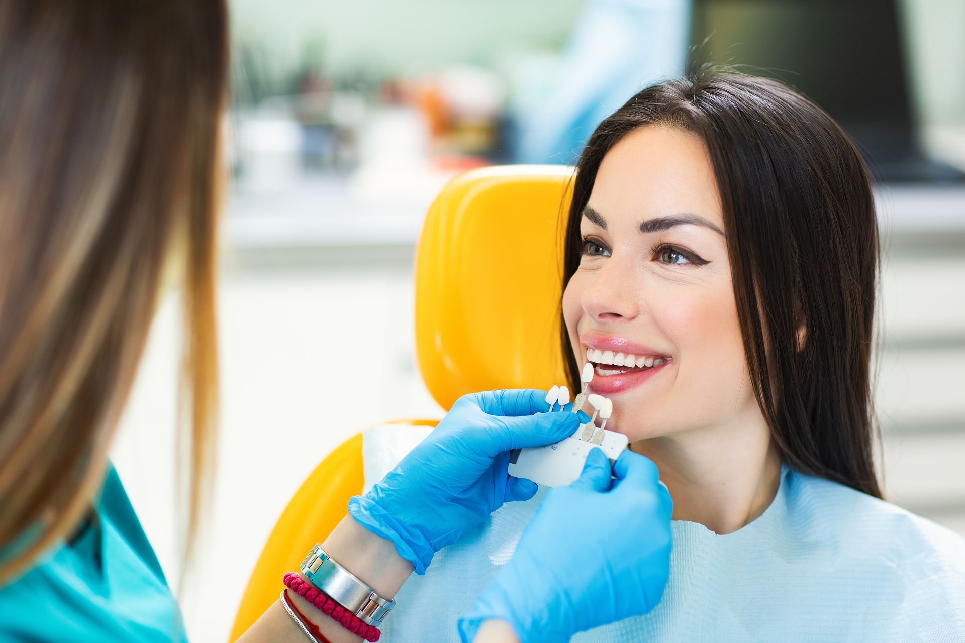 Dentist comparing tooth shade with patient during a smile consultation.