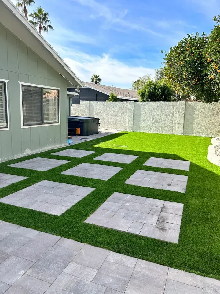 A house with a lawn and a patio in front of it.