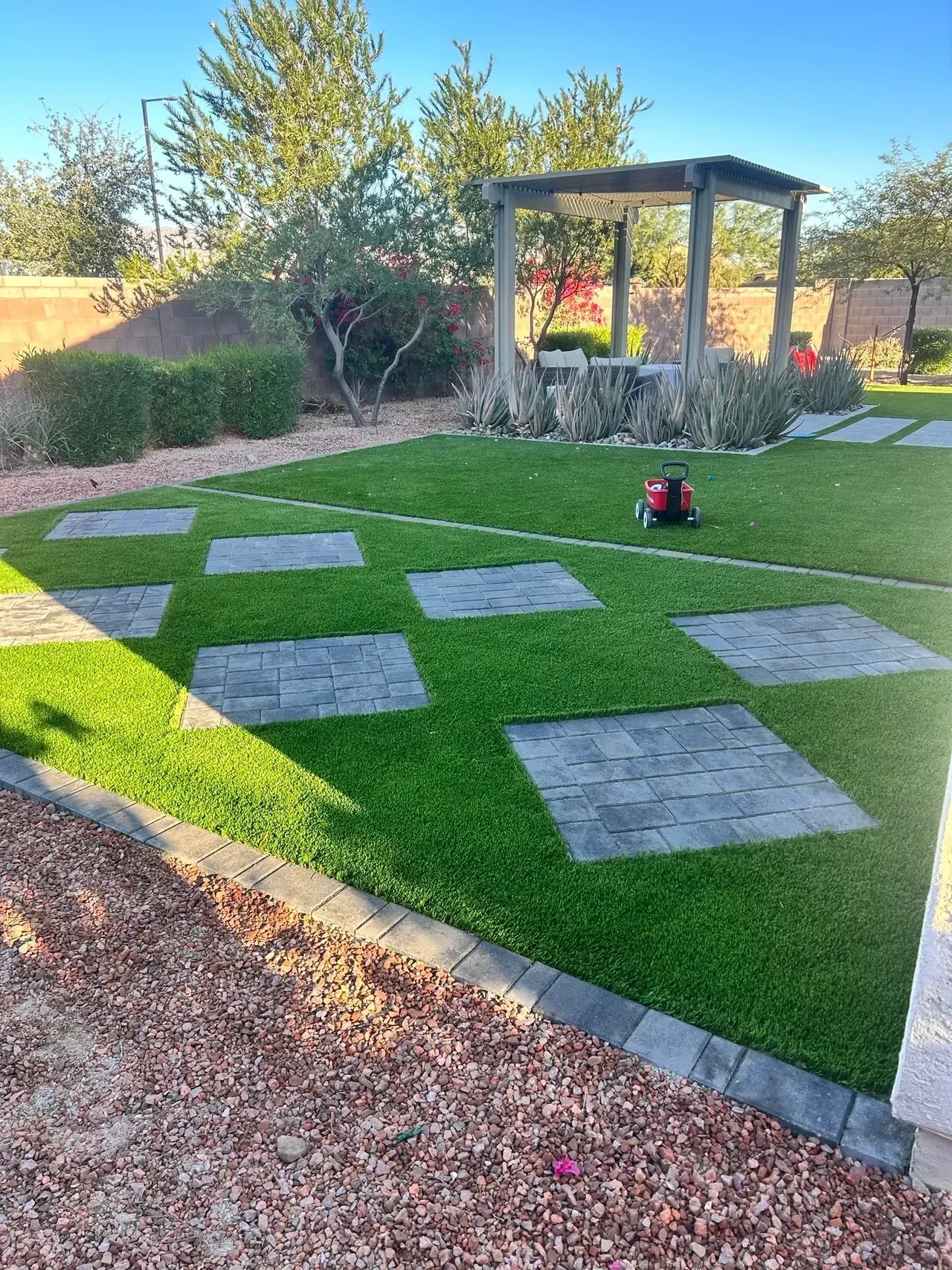 A lawn with a lawn mower and a gazebo in the background.