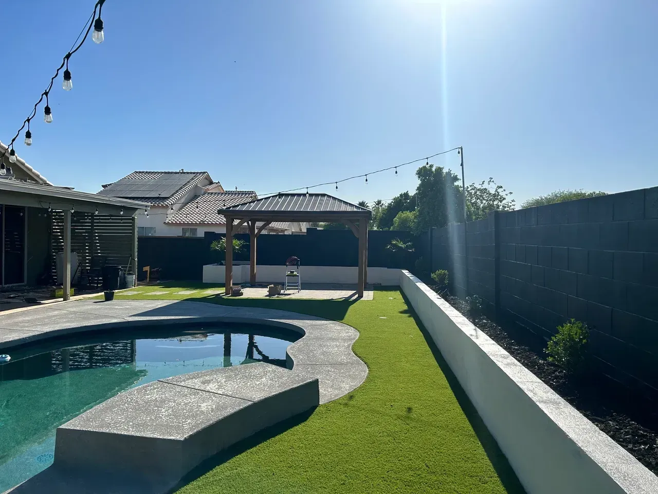 There is a swimming pool in the backyard of a house.