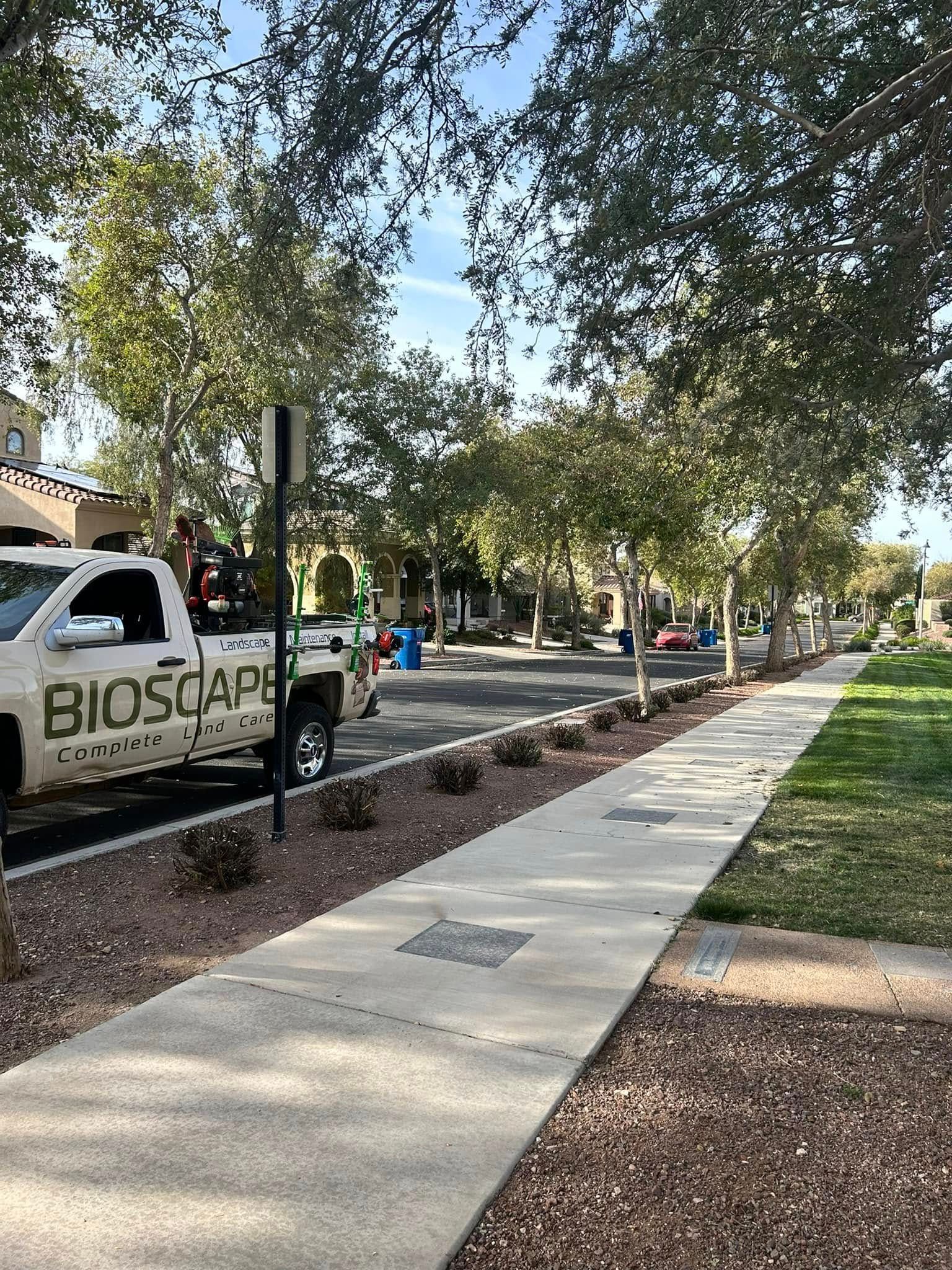 A white truck is parked on the side of the road next to a sidewalk.