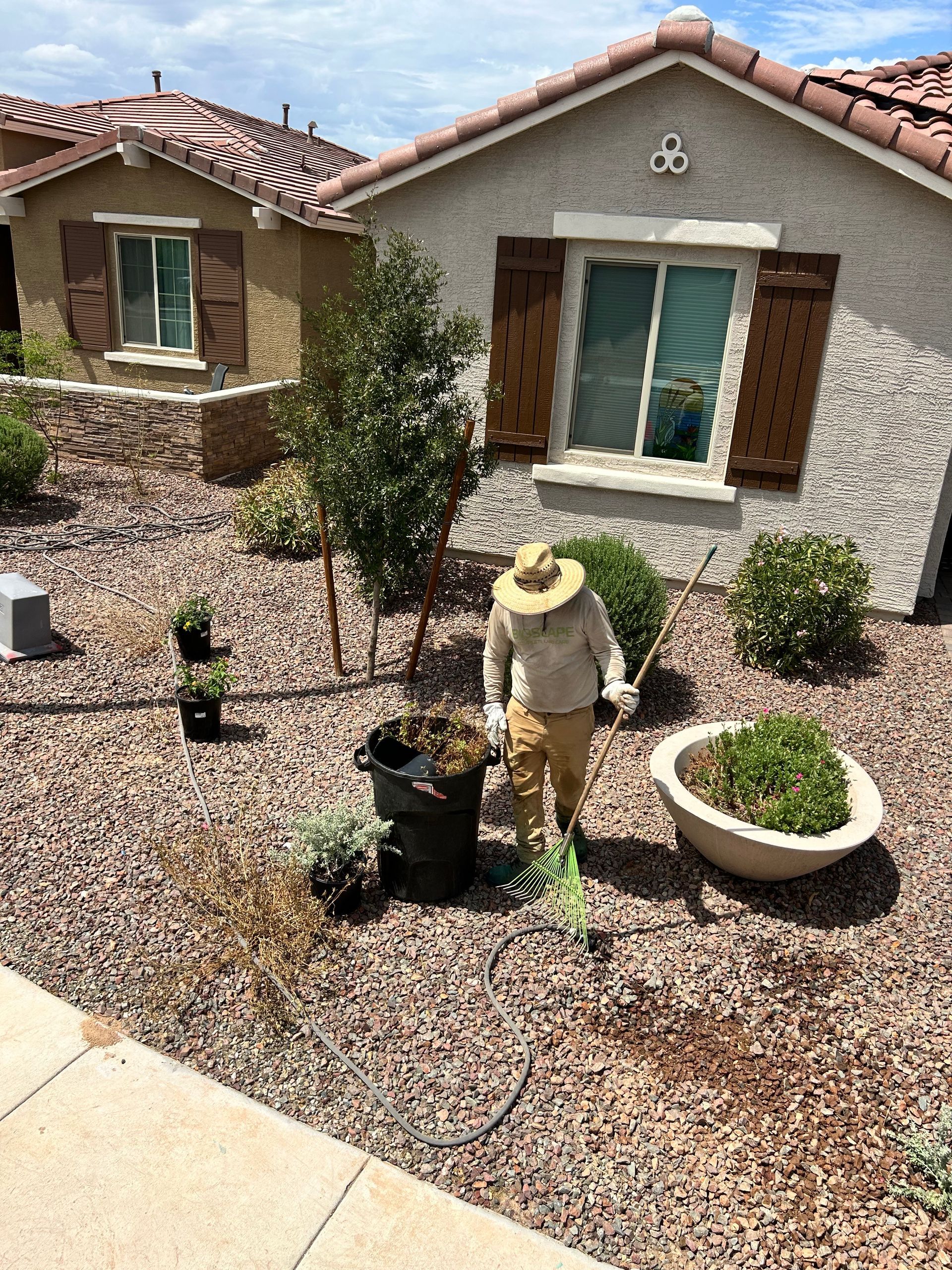 A man in a hat is standing in a garden in front of a house.