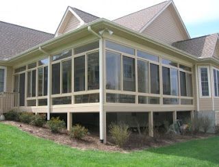 A screened in porch with a lot of windows on the side of a house.