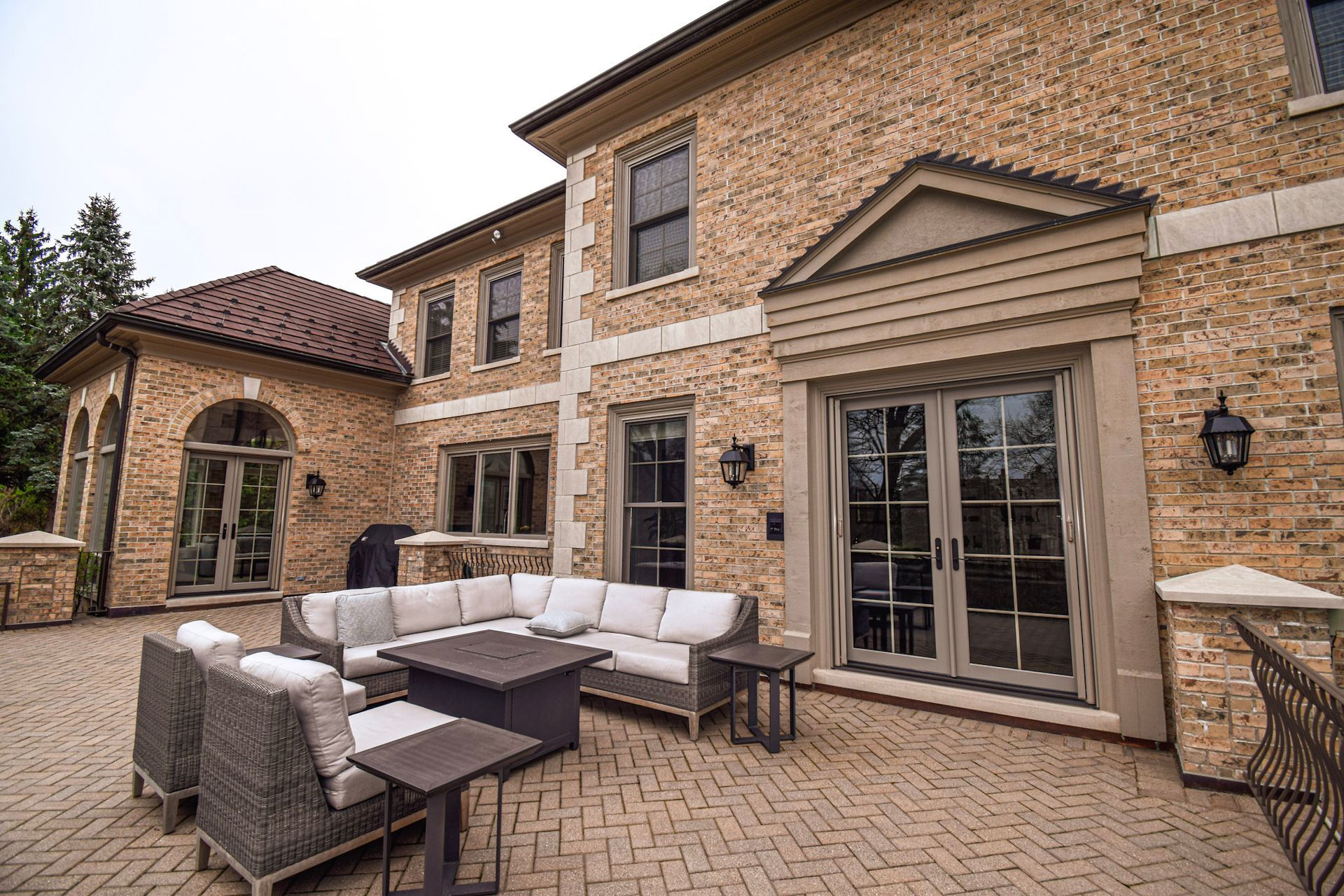 Outdoor patio of a brick house with seating and a fire pit.