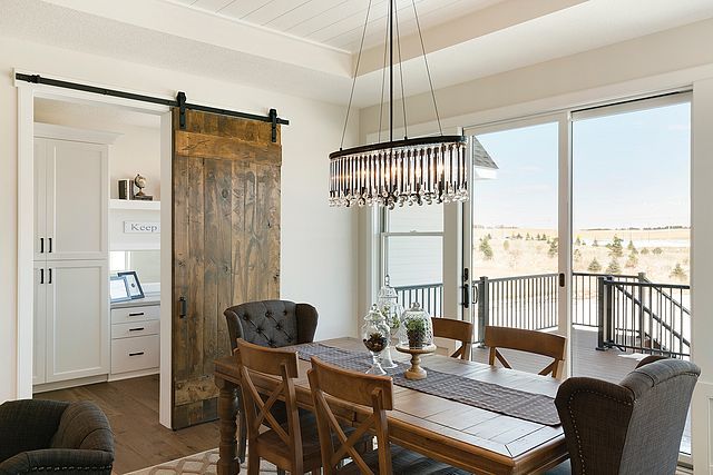 A dining room with a wooden table and chairs and a sliding barn door.