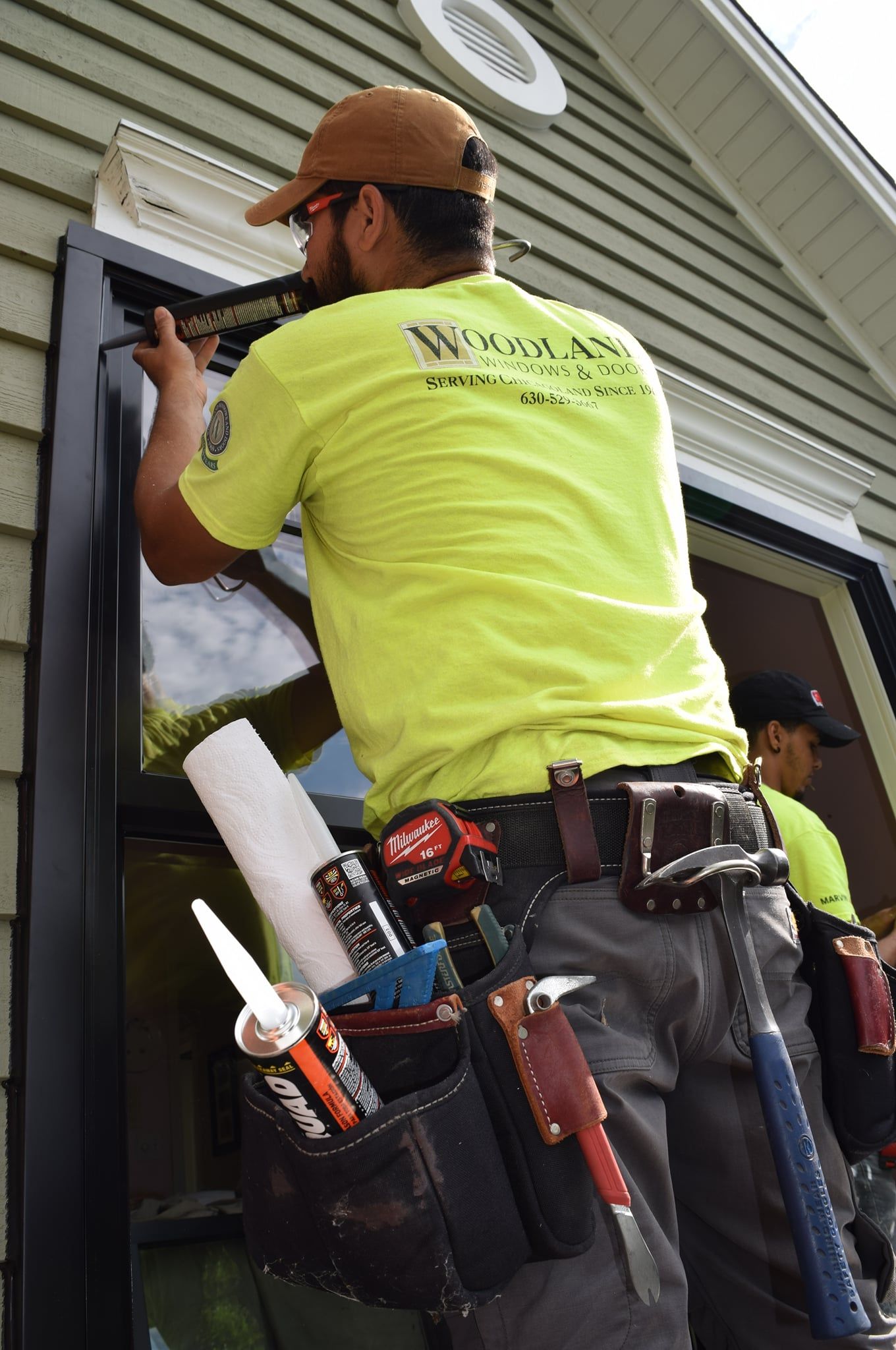 A man in a yellow shirt is working on a window.