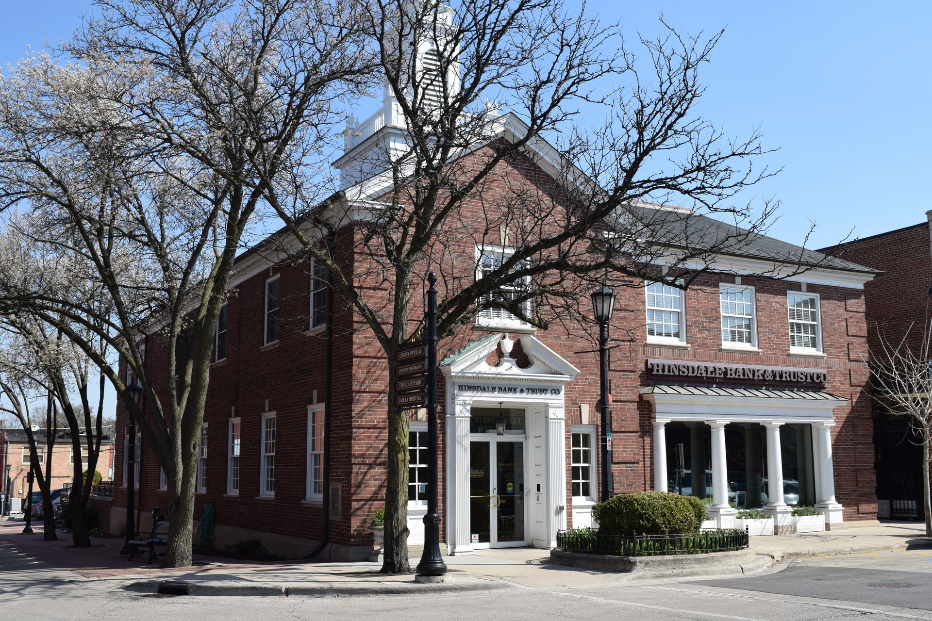 A large brick building with a clock tower and a store in front of it.